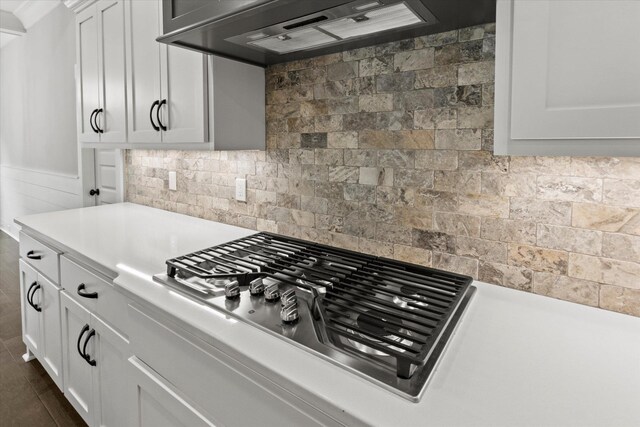 kitchen with backsplash, white cabinetry, premium range hood, and stainless steel gas cooktop