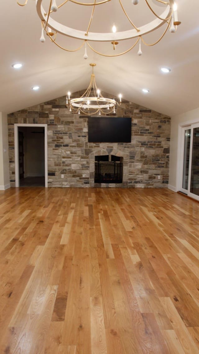 unfurnished living room with a fireplace, vaulted ceiling, and hardwood / wood-style flooring