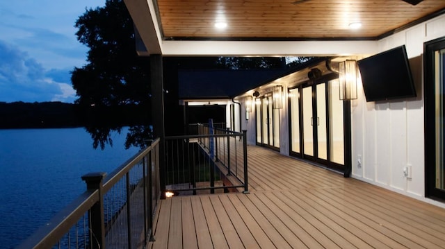 deck at dusk featuring a water view