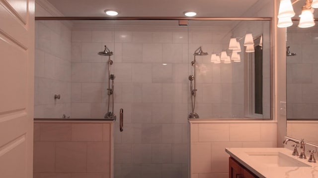 bathroom with vanity, a shower with door, ornamental molding, and tile walls