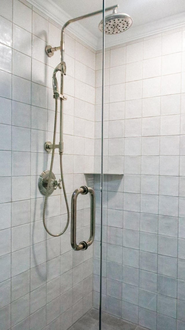 bathroom featuring a shower with shower door and ornamental molding