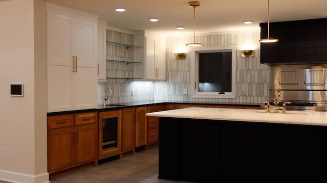 kitchen featuring decorative backsplash, light stone countertops, sink, and decorative light fixtures