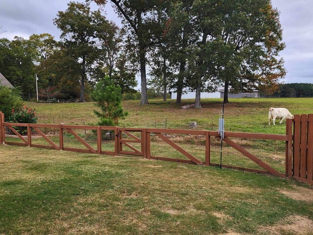 view of gate featuring a lawn and a rural view