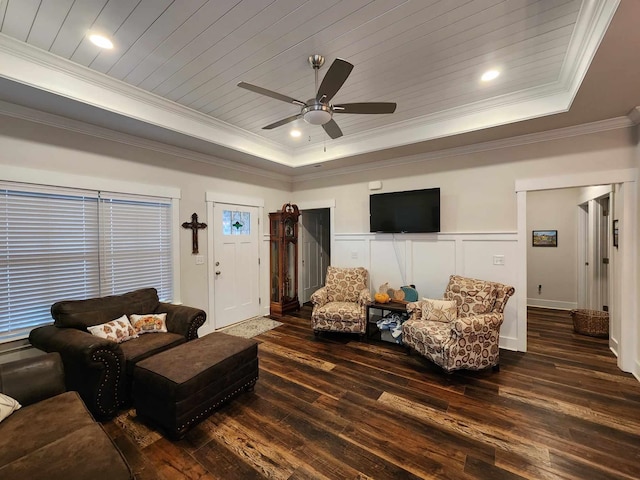 living room with a raised ceiling, ceiling fan, dark wood-type flooring, and ornamental molding