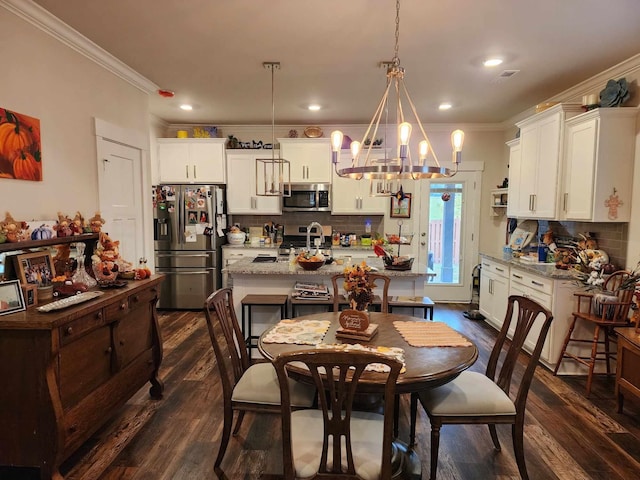 dining room featuring a notable chandelier, sink, ornamental molding, and dark wood-type flooring