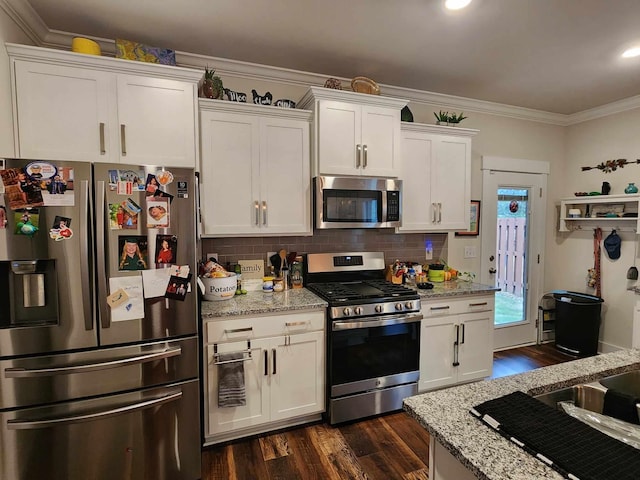 kitchen with appliances with stainless steel finishes, tasteful backsplash, light stone counters, crown molding, and white cabinets