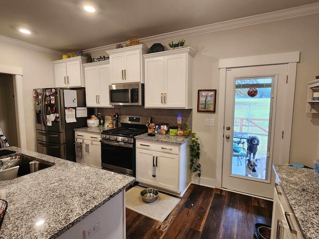 kitchen with light stone countertops, white cabinetry, sink, and stainless steel appliances