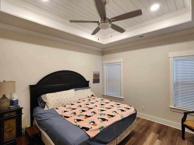 bedroom featuring ceiling fan, dark hardwood / wood-style flooring, ornamental molding, and a tray ceiling