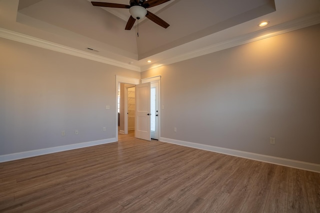 spare room featuring hardwood / wood-style flooring, ornamental molding, a raised ceiling, and ceiling fan