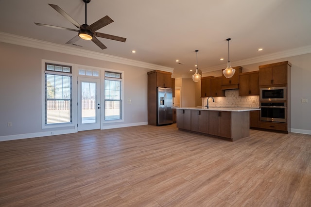 kitchen featuring an island with sink, sink, backsplash, appliances with stainless steel finishes, and pendant lighting