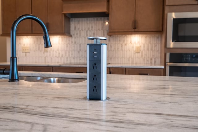 kitchen with built in microwave, decorative backsplash, sink, and stainless steel oven