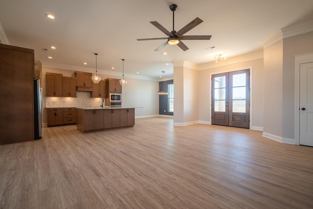 kitchen featuring a center island with sink, sink, pendant lighting, stainless steel appliances, and decorative backsplash