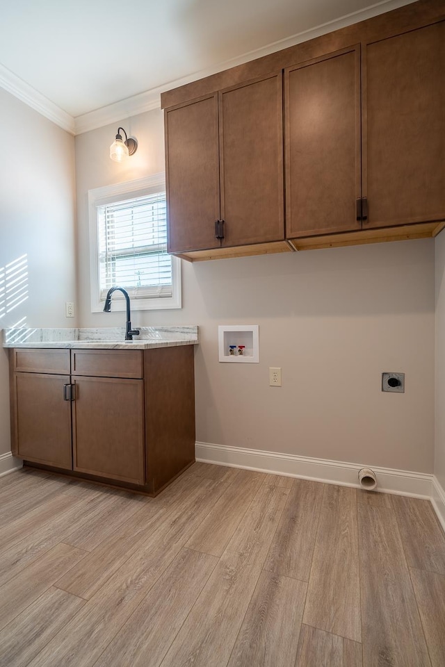 clothes washing area featuring hookup for a washing machine, light hardwood / wood-style floors, electric dryer hookup, ornamental molding, and cabinets