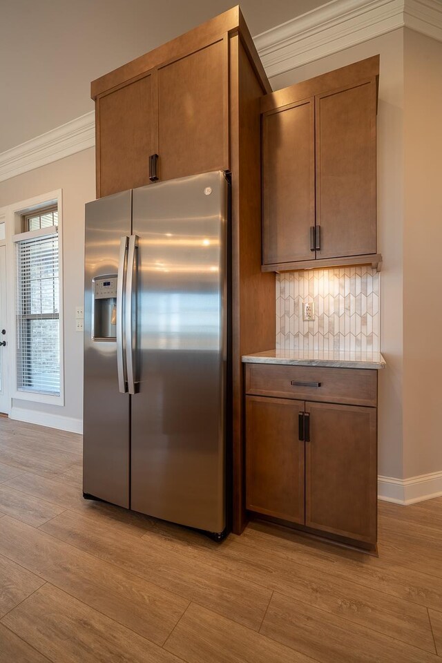 kitchen with ornamental molding, light hardwood / wood-style floors, stainless steel fridge with ice dispenser, and backsplash