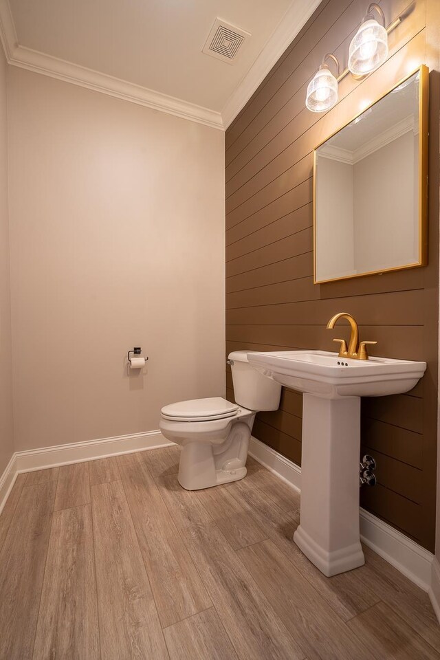 bathroom with toilet, wood-type flooring, and ornamental molding