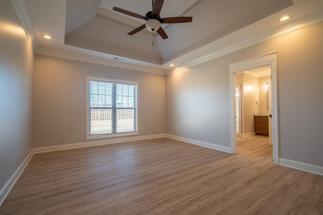 spare room with a tray ceiling, ornamental molding, ceiling fan, and light hardwood / wood-style flooring