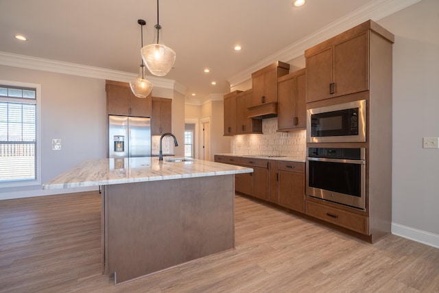 kitchen with appliances with stainless steel finishes, sink, decorative light fixtures, a kitchen island with sink, and decorative backsplash