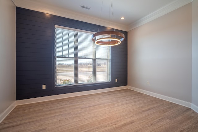 empty room with hardwood / wood-style flooring, crown molding, and wood walls