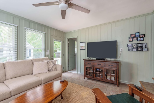  - living room with ceiling fan, light tile patterned floors, baseboards, and crown molding