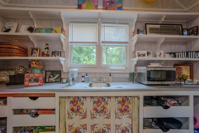  - kitchen featuring stainless steel microwave, a sink, open shelves, and light countertops