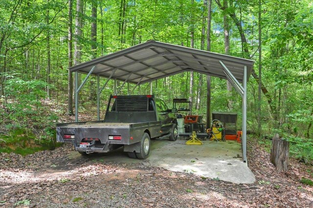 - view of parking / parking lot featuring a carport, a forest view, and driveway