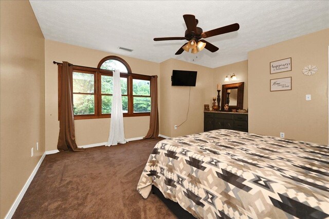  - bedroom featuring dark carpet, baseboards, ensuite bath, ceiling fan, and a textured ceiling