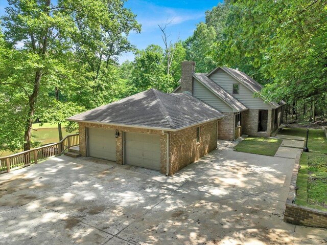  - view of side of home with brick siding, a shingled roof, a chimney, and driveway