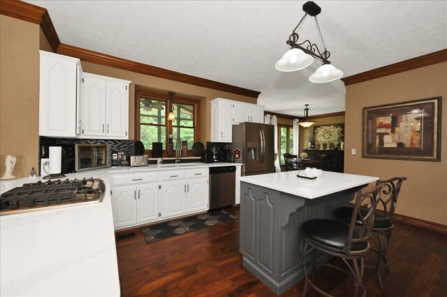  - kitchen featuring stainless steel appliances, crown molding, white cabinetry, dark wood-style flooring, and a sink