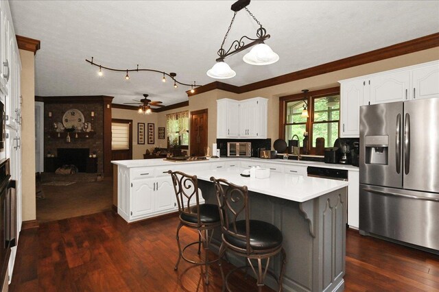  - kitchen with stainless steel fridge, a fireplace, a peninsula, a ceiling fan, and white cabinets