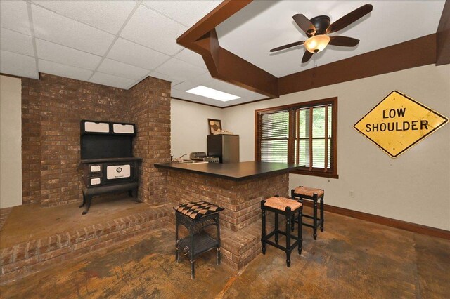  - bar area with a ceiling fan, baseboards, concrete flooring, and a drop ceiling