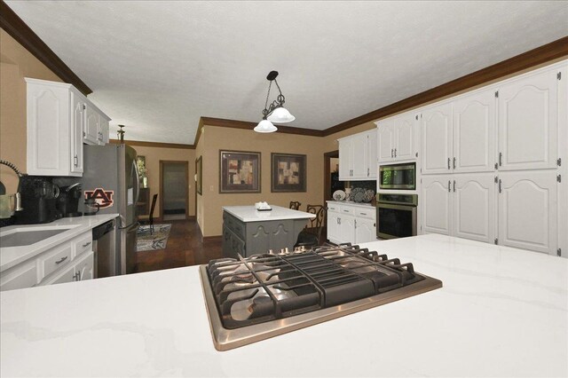  - kitchen featuring stainless steel appliances, white cabinetry, a sink, a kitchen island, and ornamental molding