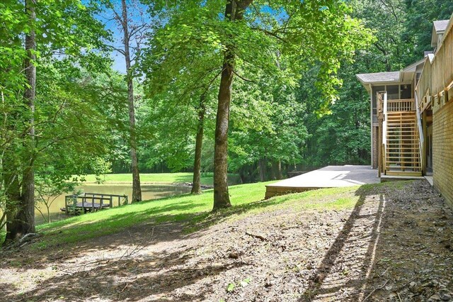  - view of grassy yard featuring stairway, a patio, and view of wooded area