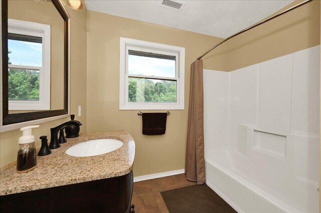  - full bath with plenty of natural light, baseboards, vanity, and shower / tub combo