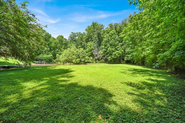  - view of grassy yard with a wooded view
