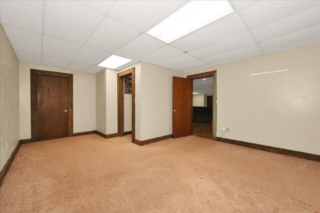  - spare room with a drop ceiling, light carpet, and baseboards