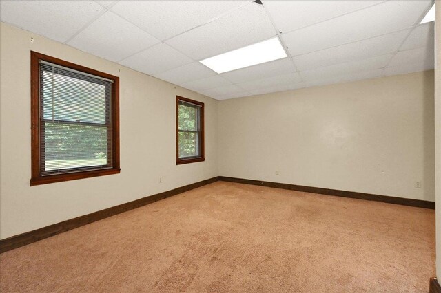  - spare room with light carpet, a paneled ceiling, and baseboards