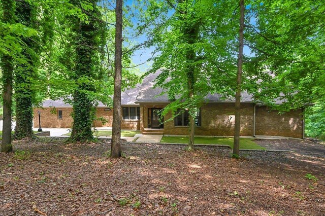  - rear view of house featuring a shingled roof and brick siding