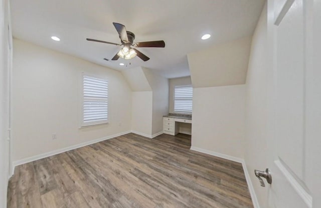 bonus room featuring vaulted ceiling, hardwood / wood-style floors, ceiling fan, and built in desk