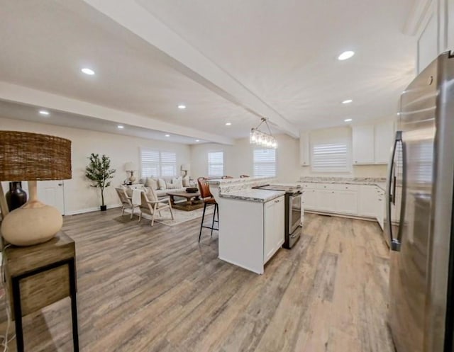 kitchen with hanging light fixtures, appliances with stainless steel finishes, a kitchen breakfast bar, a kitchen island, and white cabinets