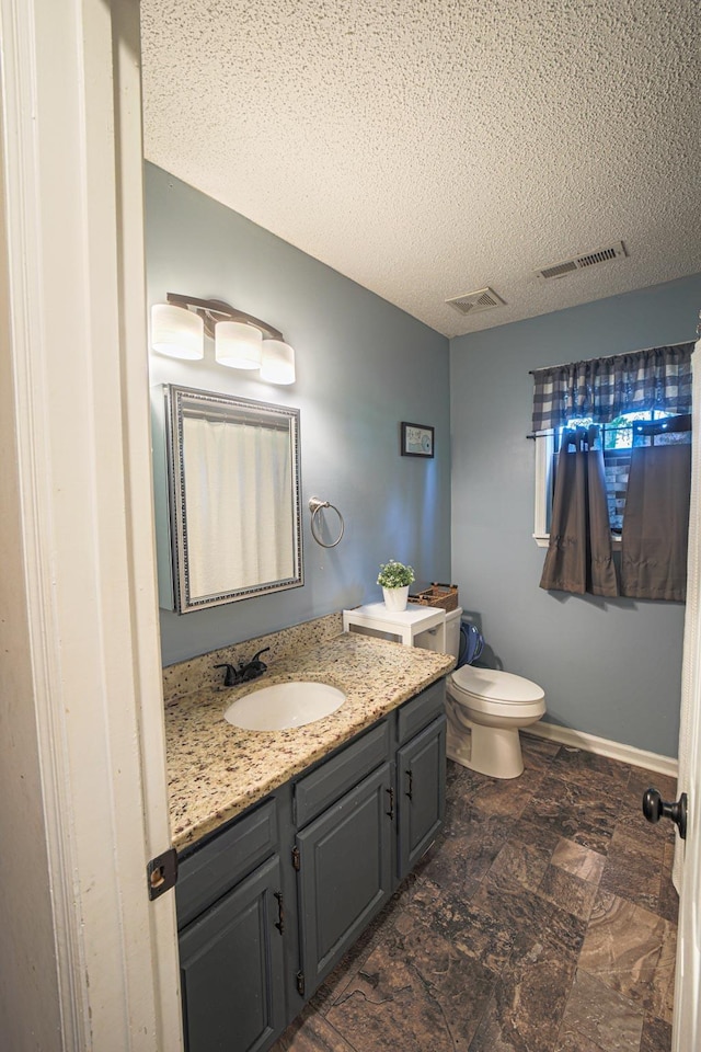  - bathroom with vanity, a textured ceiling, toilet, and baseboards
