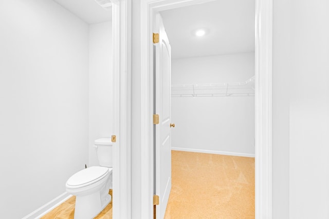  - bathroom featuring toilet, baseboards, and a spacious closet