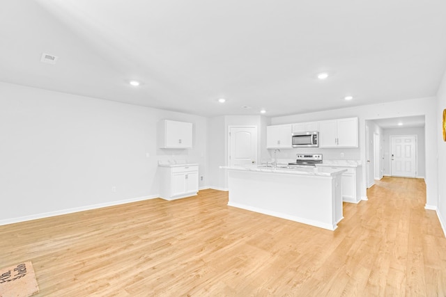  - kitchen featuring stainless steel microwave, range, light wood-style floors, a sink, and recessed lighting