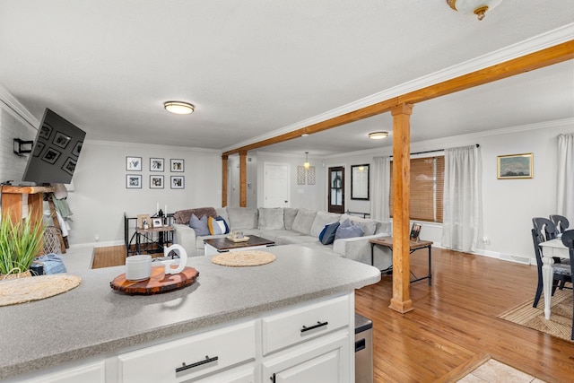 kitchen featuring white cabinets, light wood-type flooring, ornate columns, and ornamental molding