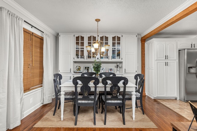 dining room featuring ornamental molding, a chandelier, a textured ceiling, and wood-type flooring