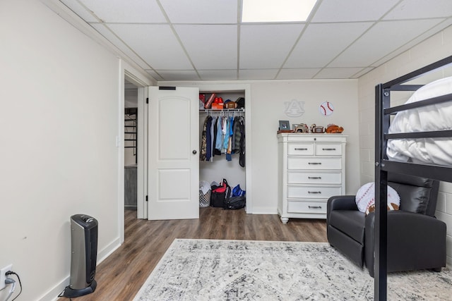 bedroom with a drop ceiling, dark hardwood / wood-style floors, and a closet