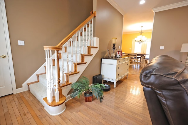 stairs featuring a notable chandelier, hardwood / wood-style flooring, and ornamental molding