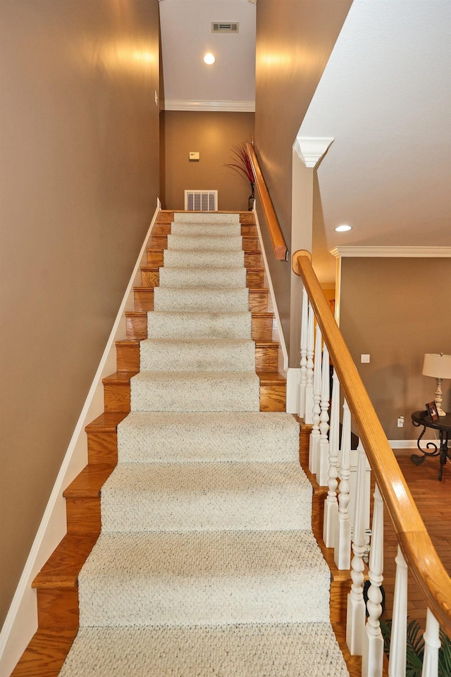 stairs featuring wood-type flooring and crown molding