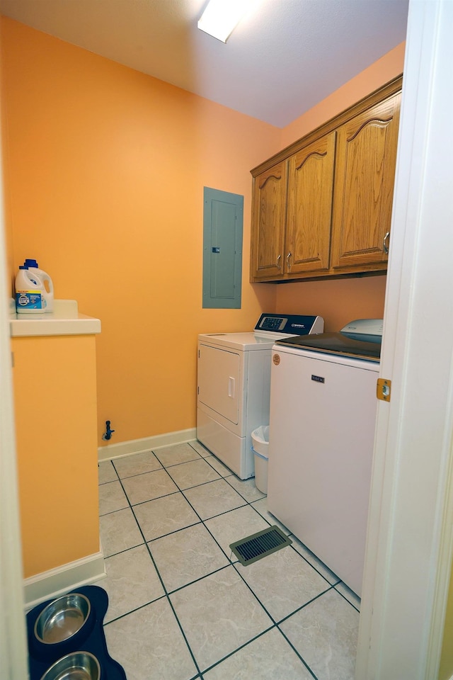 washroom featuring electric panel, light tile patterned floors, cabinets, and washing machine and dryer