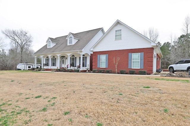 cape cod house featuring covered porch and a front lawn