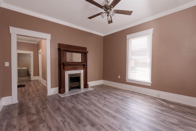 unfurnished living room featuring ceiling fan, a fireplace, wood finished floors, baseboards, and ornamental molding